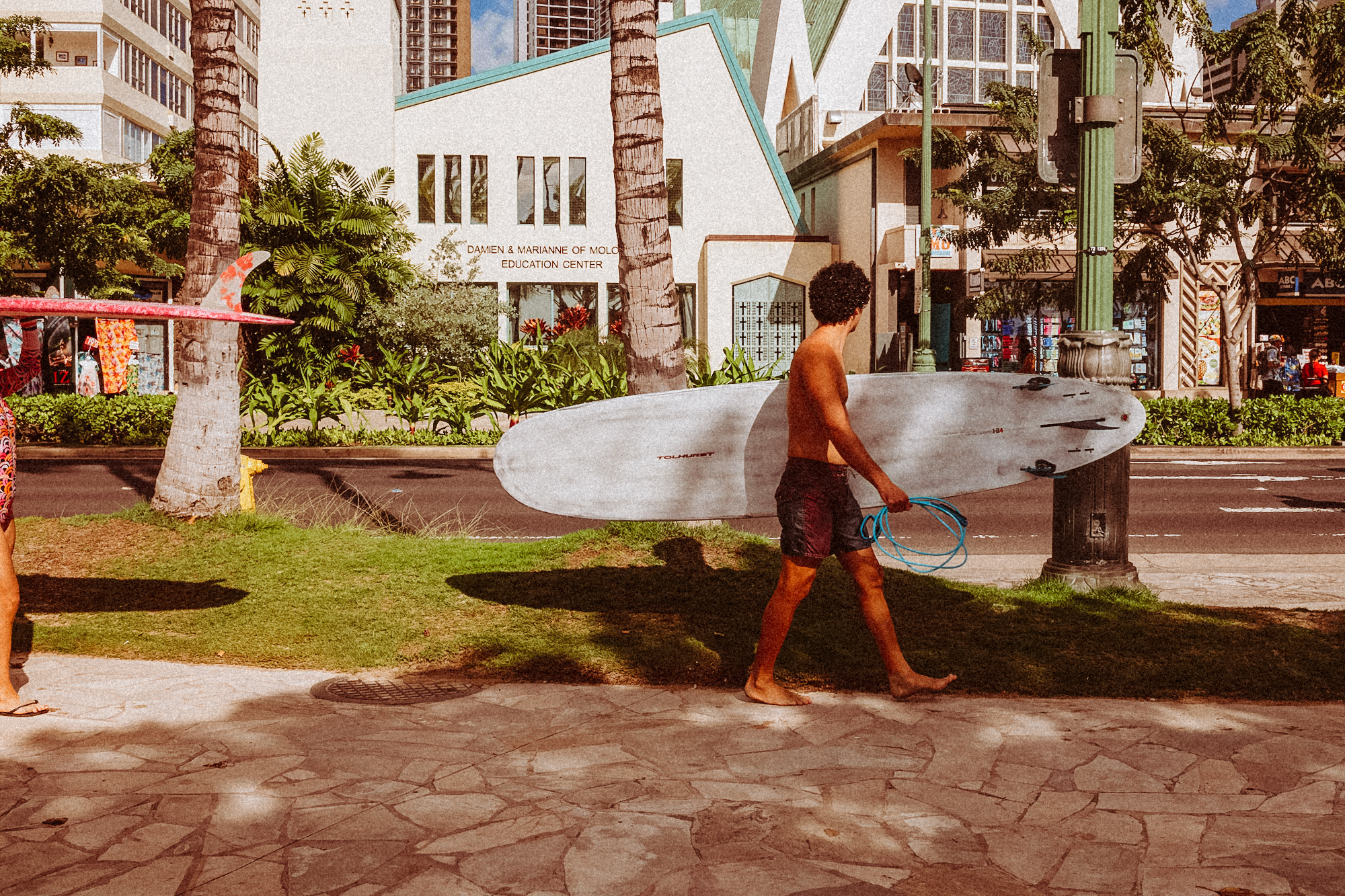 Guy walking on Waikiki Beach with a surfboard